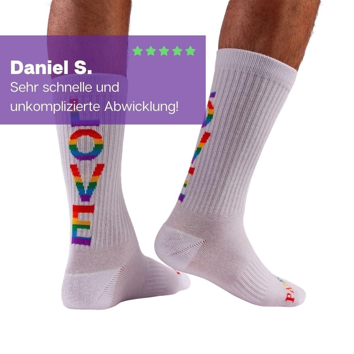 Füße mit weißen Pride Tennissocken und buntem LOVE Schriftzug von PATRON SOCKS