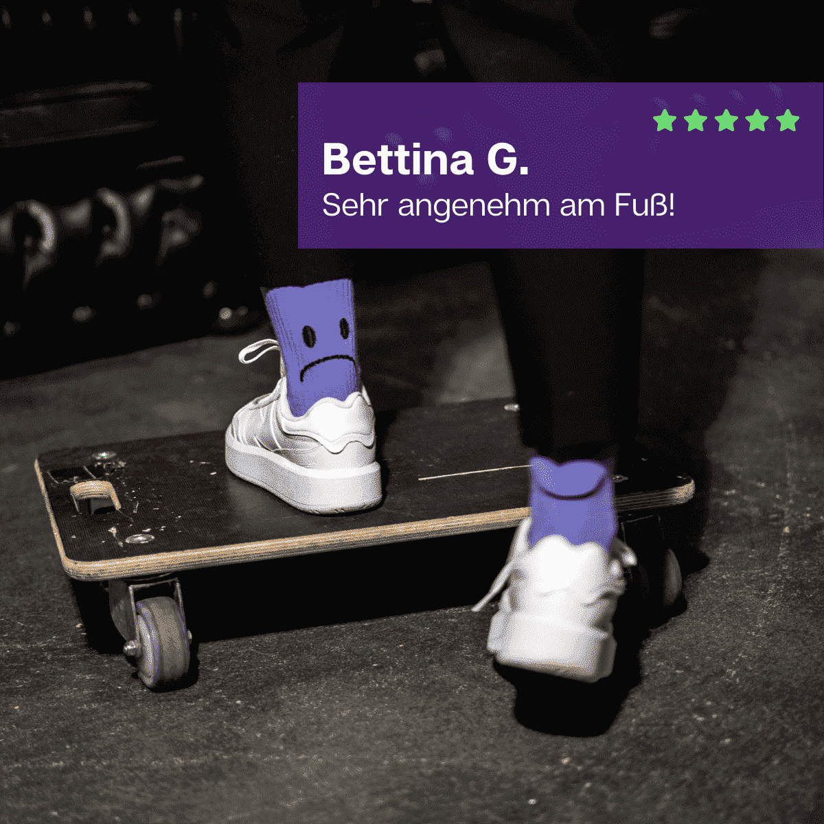 Füße in weißen Schuhen auf Möbelroller stehend mit lila Sportsocken mit Smiley Motiv von PATRON SOCKS