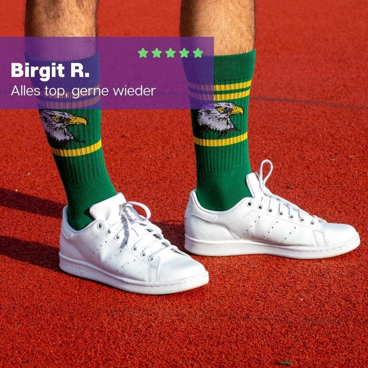 Mann in weißen Turnschuhen mit grünen Sportsocken mit Falken Motiv