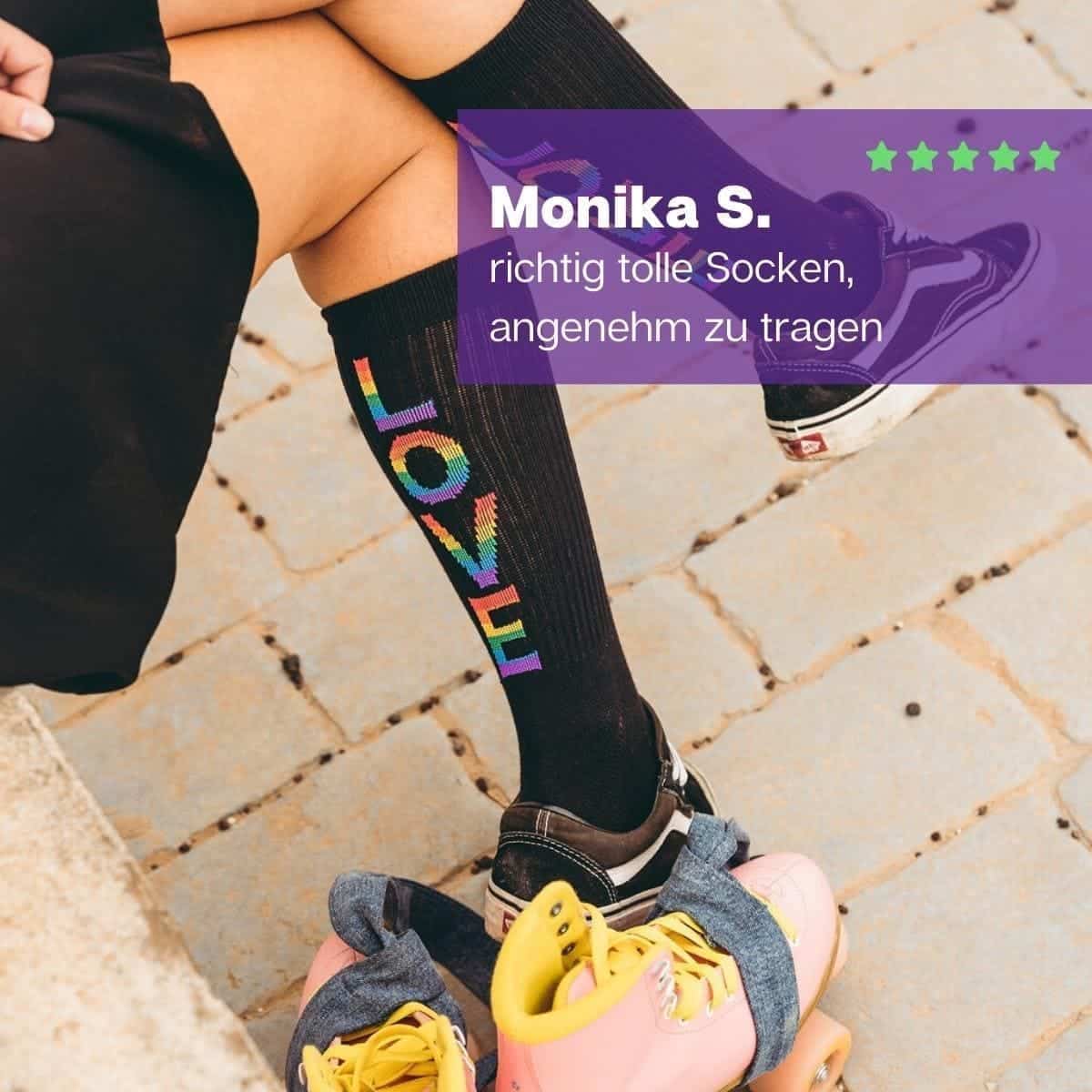 Mädchen in Turnschuhen sitzend mit schwarzen Pride Tennissocken und buntem LOVE Schriftzug von PATRON SOCKS